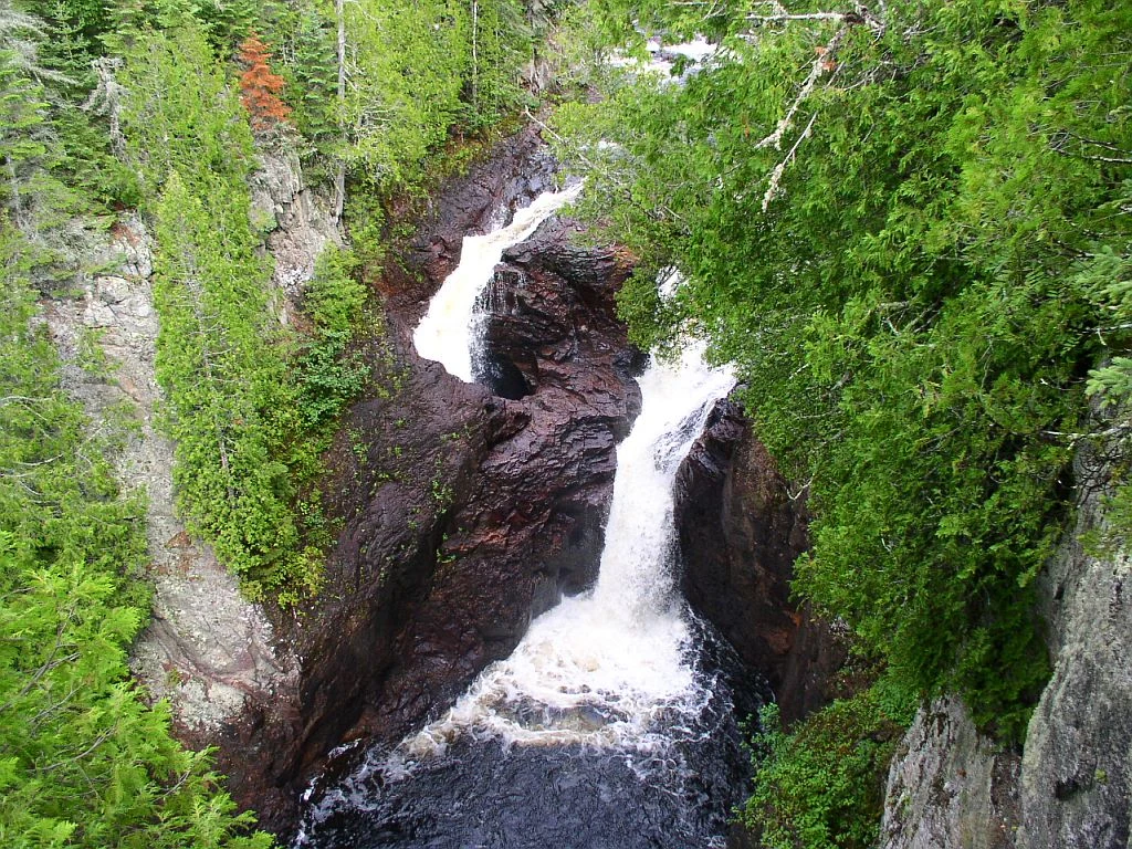 森の中の二つの滝。写真左の水は岩の穴へ、右の水は白いしぶきを上げて下の水面へ落ちる